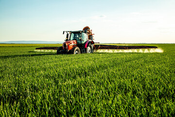 Tractor spraying pesticide on green farm field © oticki