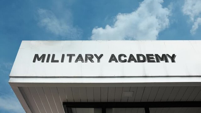A military academy word sign displayed on a formal, institutional building under a clear blue sky, symbolizing officer training, defense education, and discipline