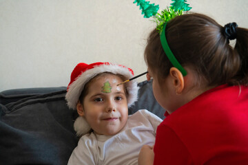 The older sister gives her younger sisters Christmas face painting.