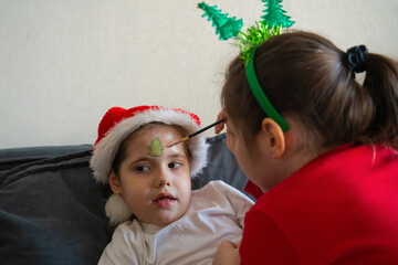 The older sister gives her younger sisters Christmas face painting.