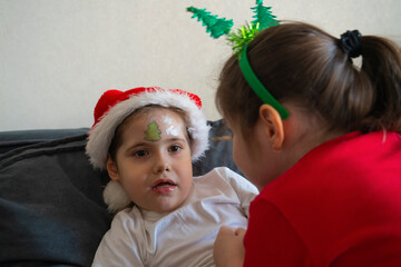 The older sister gives her younger sisters Christmas face painting.
