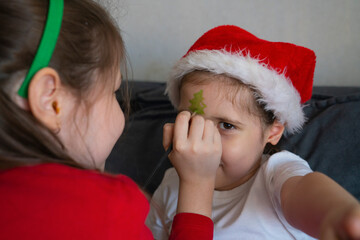 The older sister gives her younger sisters Christmas face painting.