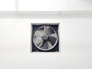 A square exhaust fan mounted in a white wall, centered in the frame.