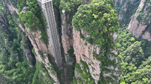 Aerial view of the Bailong Elevator cutting through the rugged cliff face surrounded by lush green vegetation, Zhangjiajie, China.
