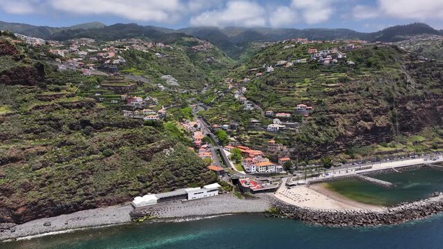 Scenic Calheta seaside resort on Madeira coastline, drone pullback riser reveal
