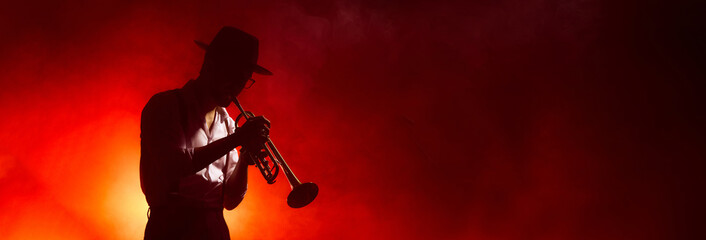 Jazz musician in hat playing trumpet in red atmospheric light. Concept of music industry visuals, art and graphic design use, and audio brand promotion materials. Banner