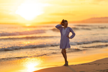 Fototapeta premium Woman enjoying golden sunset on tropical beach