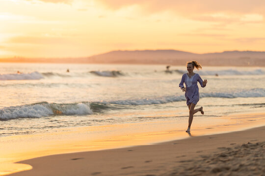 Young woman running enjoying freedom on beach sunset - Powered by Adobe