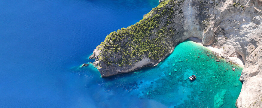 Aerial drone ultra wide panoramic photo of tropical exotic bay with crystal clear turquoise sea and sea caves forming a blue lagoon visited by small yachts and boats - Powered by Adobe