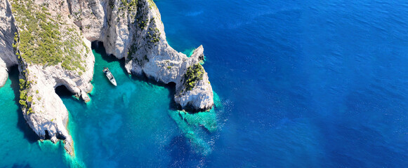 Aerial drone top down ultra wide photo with copy space of inflatable speed boat anchored in tropical exotic rocky island with emerald crystal clear sea