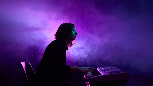 Pianist sitting at electronic keyboard surrounded by purple smoke. Concept of music industry promotion, SMM musicians and clubs, and visual branding for modern campaigns.