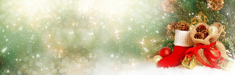 Christmas background with decorative Santa red boot and gift bag, balls, branch and cones for tree decoraton. New Year winter holidays fantasy card with decor and copy space, wide panoramic banner.