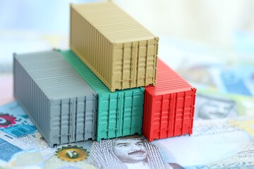 Bahraini dinar currency money bills and toy cargo containers close up. The concept of shipping and...