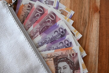 Black partmone with british pound money. United Kindom bills in leather wallet for commerce concept.