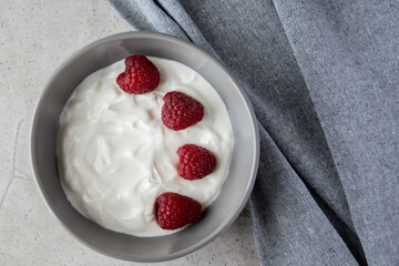 Gray ceramic bowl and natural yogurt with berries on the stone marble table.