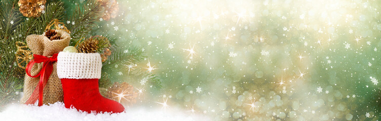 Christmas background with decorative Santa red boot and gift bag, branch and pine cones for tree decoraton. New Year winter holidays fantasy card with decor and copy space, wide panoramic banner.