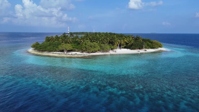 Aerial view of an island with palm trees surrounded by turquoise water, contrasting with the deep blue sea, Kendhoo, Baa Atoll, Maldives.