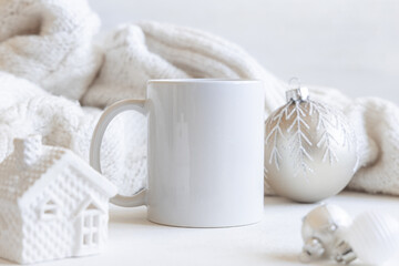 White blank coffee mug near white knitted sweater and Christmas decor, winter Holiday mockup
