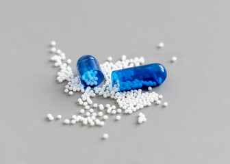 Opened Blue Medical capsule to show white granules on grey closeup. Medicine and Healthcare concept