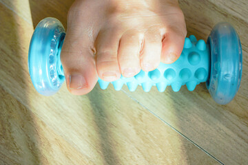 Foot using spiky massage roller for self-massage therapy, close-up. Represents relieving muscle soreness, post-workout relaxation, myofascial release technique, circulation boost, and preventive care.