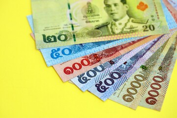 Obraz premium Thai baht money bills in big amount on yellow close up. Finance and banking concept