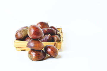 Close up of chestnuts stacked and in a basket on a white background.