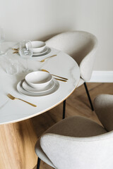 Elegant white dish setting with cutlery on a marble dining table in a modern space