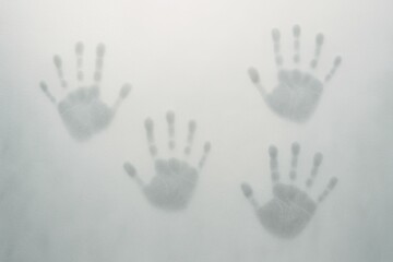 Obraz premium Three handprints on foggy glass surface with soft light and mist