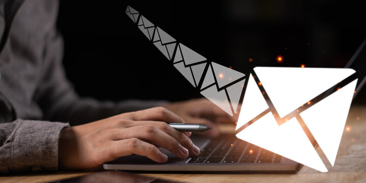 A digital communication concept showing a person typing on a laptop with glowing email icons, representing online messaging, email marketing, and business communication technology.