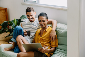 Gay couple enjoying time together at home with laptop