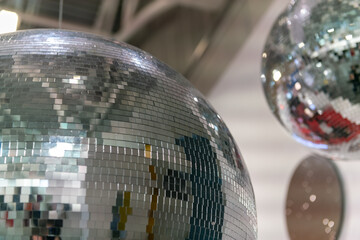 Mirror ball suspended in a nightclub with light shows, a vibrant nighttime atmosphere of music, dance, and movement, an iconic symbol of fun in clubs, parties, and soirees. New Year's Eve, web news.