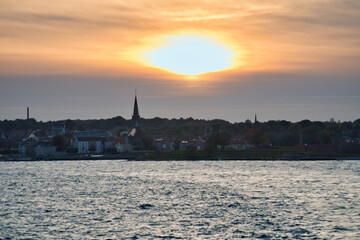 Sunset over the sea with boat trail and silhouette on the horizon