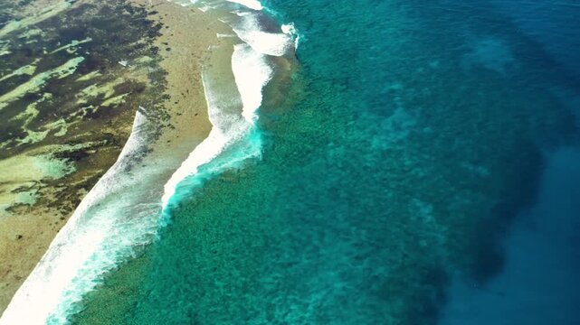 Aerial view of the meeting point of a sandy beach and turquoise ocean water, showing the contrast between the light sand and the deep blue sea, Maldives.