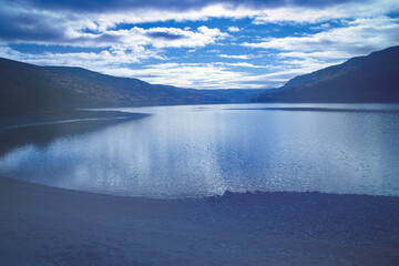 Reflecting lake under dramatic sky in autumnal natural scenery