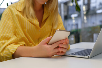 Gen Z freelancer with laptop working in a green coworking space among indoor plants, biophilic design; remote work, focus, productivity, flexible schedule, sustainable work lifestyle.