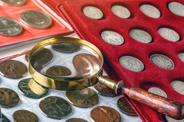 Numismatics.Antique collectible coins made of silver and gold on the table.Coins in the album.Collection of ancient coins and banknotes.Magnifying glass.Bonistics.Antikvariat.