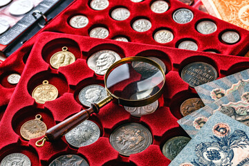 Numismatics.Antique collectible coins made of silver and gold on the table.Coins in the album.Collection of ancient coins and banknotes.Magnifying glass.Bonistics.Antikvariat.