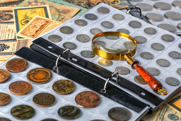 Numismatics.Antique collectible coins made of silver and gold on the table.Coins in the album.Collection of ancient coins and banknotes.Magnifying glass.Bonistics.Antikvariat.