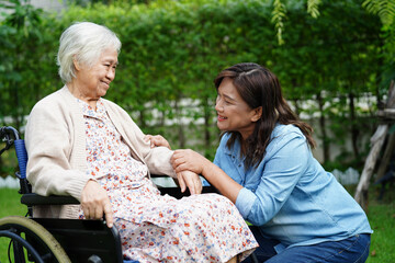 Caregiver help Asian elderly woman disability patient sitting on wheelchair in park, medical.