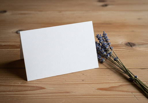 Mockup of a white business card with a sprig of lavender on a wooden background. A simple, rustic, and elegant template for spa, wellness, or artisanal branding.