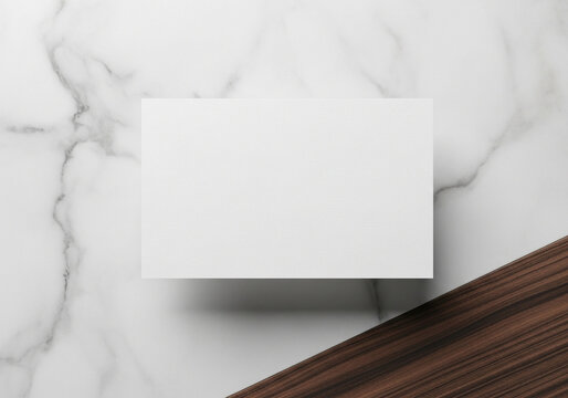 Mockup of a white business card on a stylish split background of white marble and dark wood. A clean and modern template for corporate or premium branding.