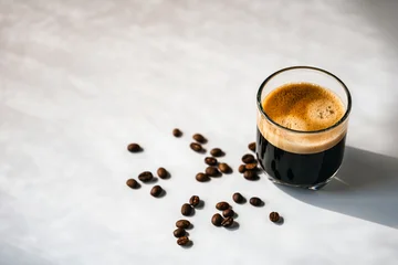 Fotobehang Café Hot espresso coffee steam rises from hot coffee in coffee glass and bean isolated on white background in Morning sunlight  © NARONG