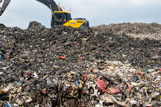 Heavy Excavator Machinery Working on a Massive Mountain of Trash at a Landfill Site