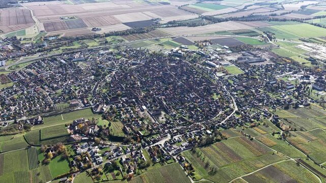 Aerial view of the clustered town of Rouffach encircled by vibrant green fields and vineyards, creating a tapestry of colors, Rouffach, Grand Est, France.