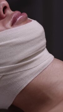 Vertical video of compression bandages with facelifting effect, facial spa treatment of female patient. Anti-aging skincare, professional beauty treatment