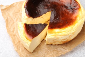 Cut Basque cheesecake on light grey textured table, closeup