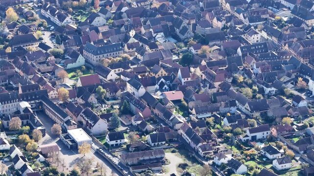 Aerial view of clustered buildings and colorful rooftops interspersed with trees, creating a dense urban tapestry, Rouffach, Grand Est, France.