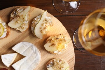 Delicious bruschettas served with camembert and wine on wooden table, flat lay