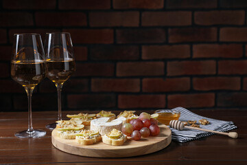 Delicious bruschettas served with camembert, grapes and wine on wooden table. Space for text