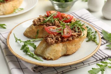 Delicious bruschettas with tuna, tomatoes and arugula on white table, closeup